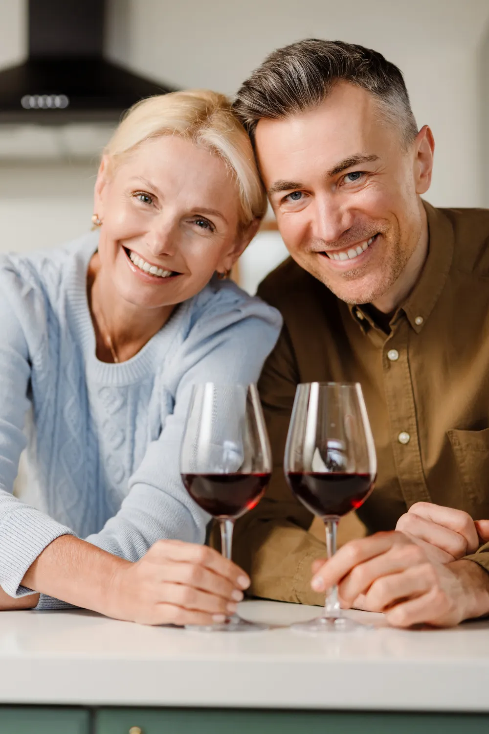 glückliches Paar in neuer Küche mit Wein